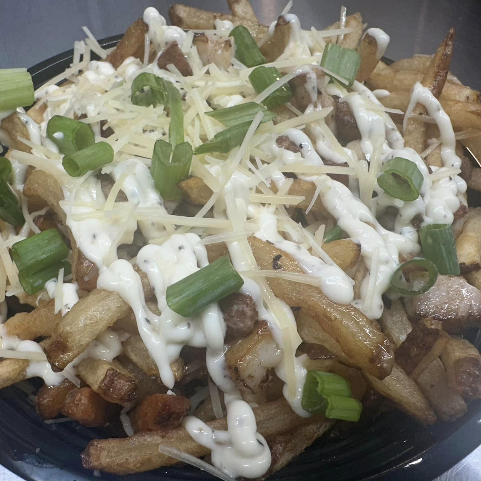 Quack Fry- award-winning hand cut fries tossed in duck fat and Parmesan cheese and topped with crispy pork belly, truffle aioli and green onion.